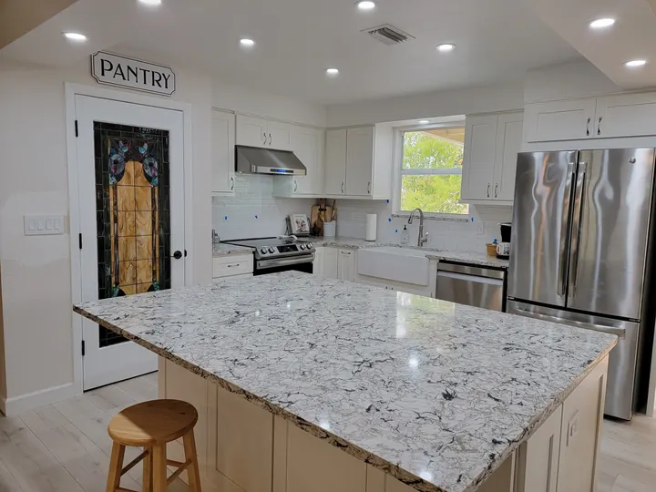 Large patterned stone kitchen island with white cabinets