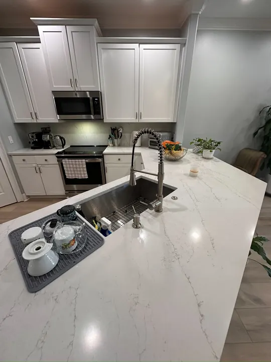White quartz kitchen island with stainless workstation sink