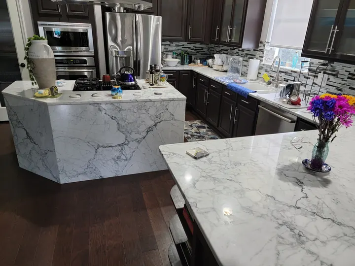 White stone waterfall island with dark kitchen cabinets