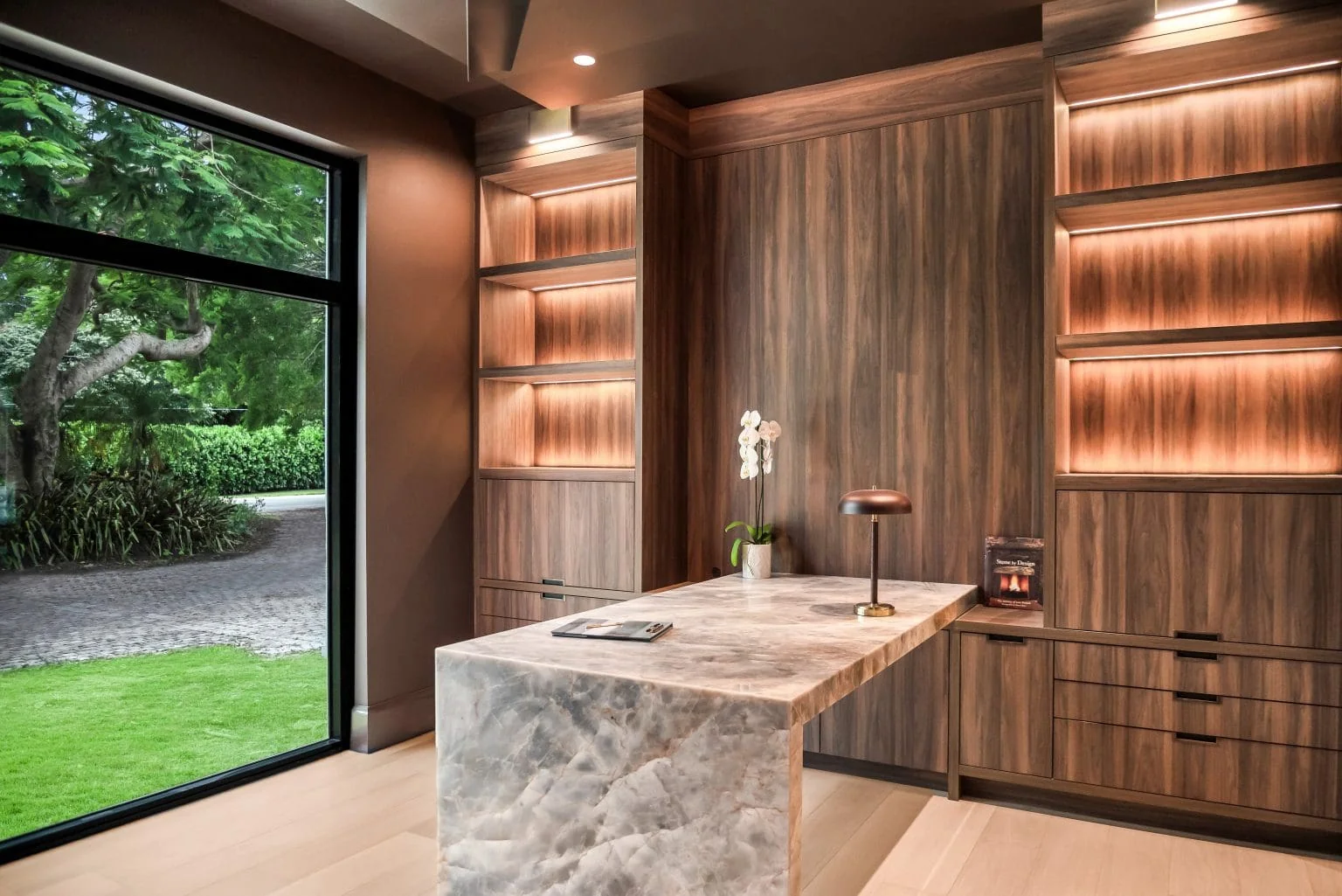 Study with illuminated walnut cabinetry and stone waterfall desk